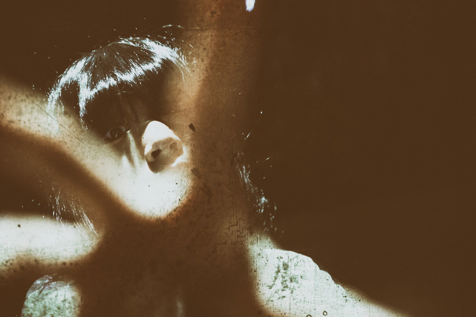 暗闇の中で不気味な表情を浮かべる女性の顔のクローズアップ［モデル：緋真煉］