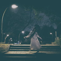 深夜の公園で不気味な動きをする女性、街灯に照らされたシルエットの写真