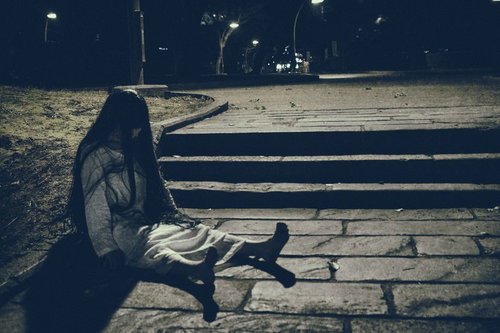 捨てられた人形のように階段に座り込む女性の姿