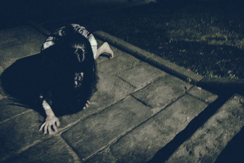 何かに取り憑かれた女性が石畳を這いつくばる