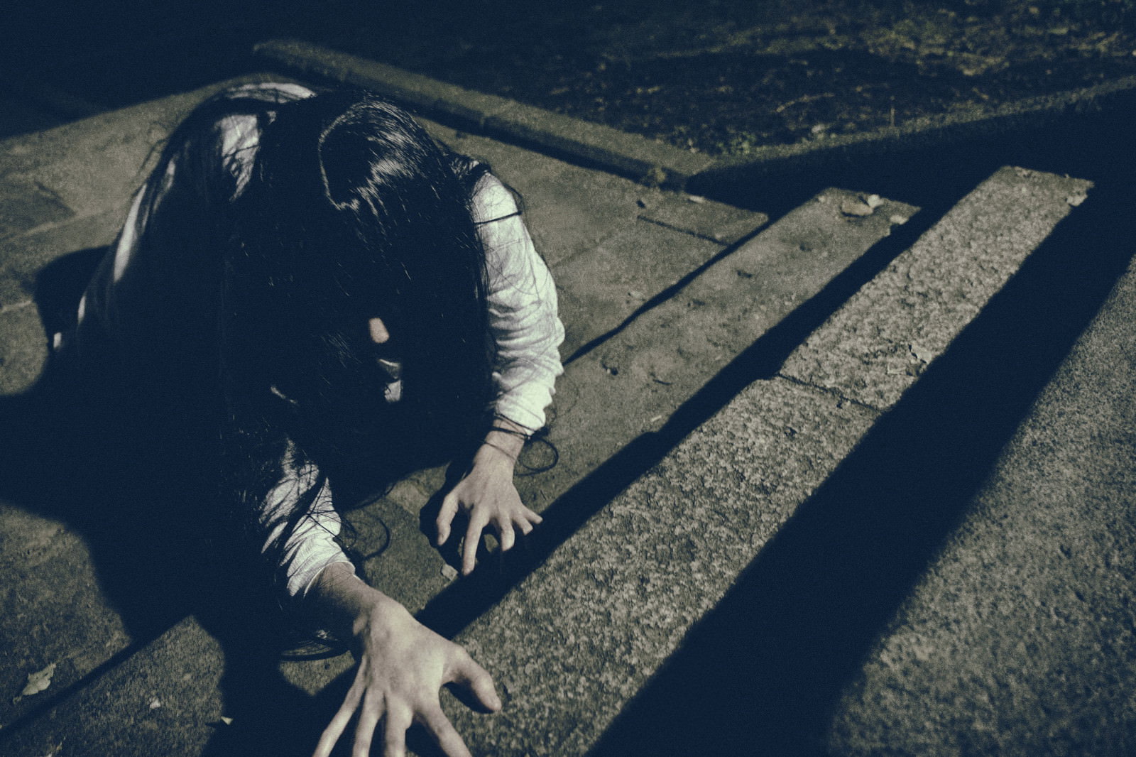 暗い階段で這いつくばるような姿勢をとる女性［モデル：緋真煉］