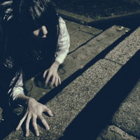 薄暗い階段を這いながら上りきろうとする女性の写真