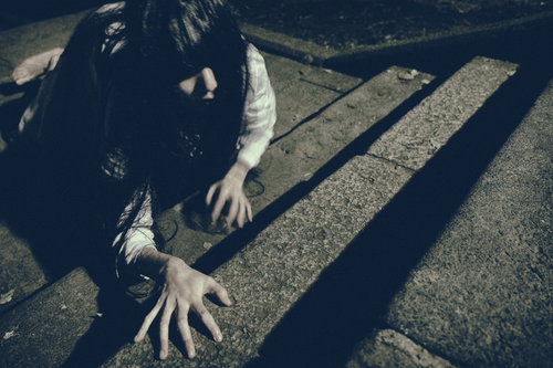 薄暗い階段を這いながら上りきろうとする女性