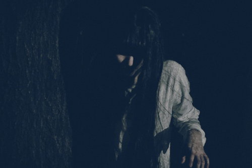 木陰に潜む恐怖、暗い夜の森で白い服の女性