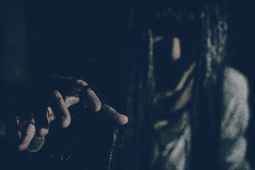 暗闇にさまよう白衣の幽霊女性、背後に複数の人影が浮かぶ恐怖のホラー