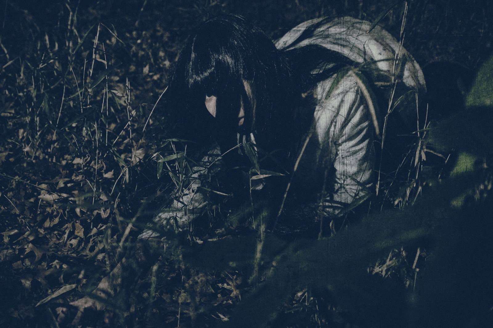深夜の草むらで身をかがめて小銭を探している女性［モデル：緋真煉］