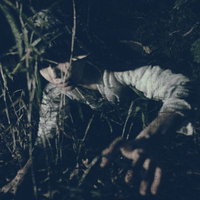 肝試しで脅かし役を担う女性が暗闇で立つ夜間の恐怖シーンの写真
