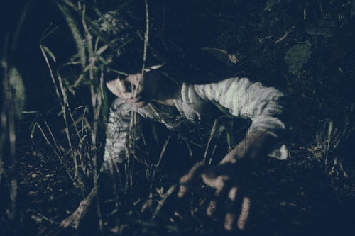 肝試しで脅かし役を担う女性が暗闇で立つ夜間の恐怖シーン