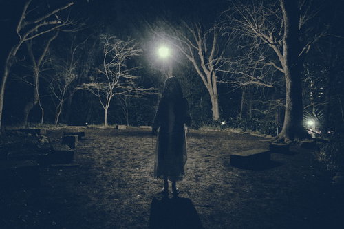 真夜中の雑木林で月明かりに照らされ仁王立ちする女性