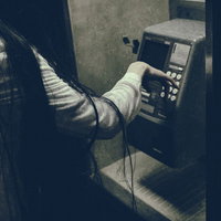 非通知の電話先で受話器を握る女性の怖い表情の写真