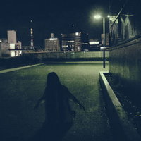 建物の物陰で膝から崩れ落ちる女性の夜景、都市の暗闇でシルエットの写真