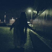 暗影から近づく亡霊の女性、街灯に浮かぶシルエットの写真