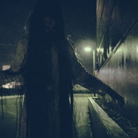 薄暗い廊下で両腕を広げて通せんぼをする女性のシルエットの写真