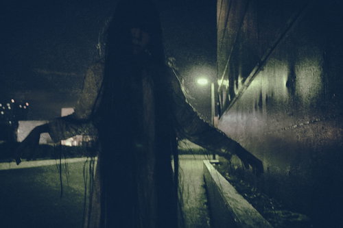 薄暗い廊下で両腕を広げて通せんぼをする女性のシルエット