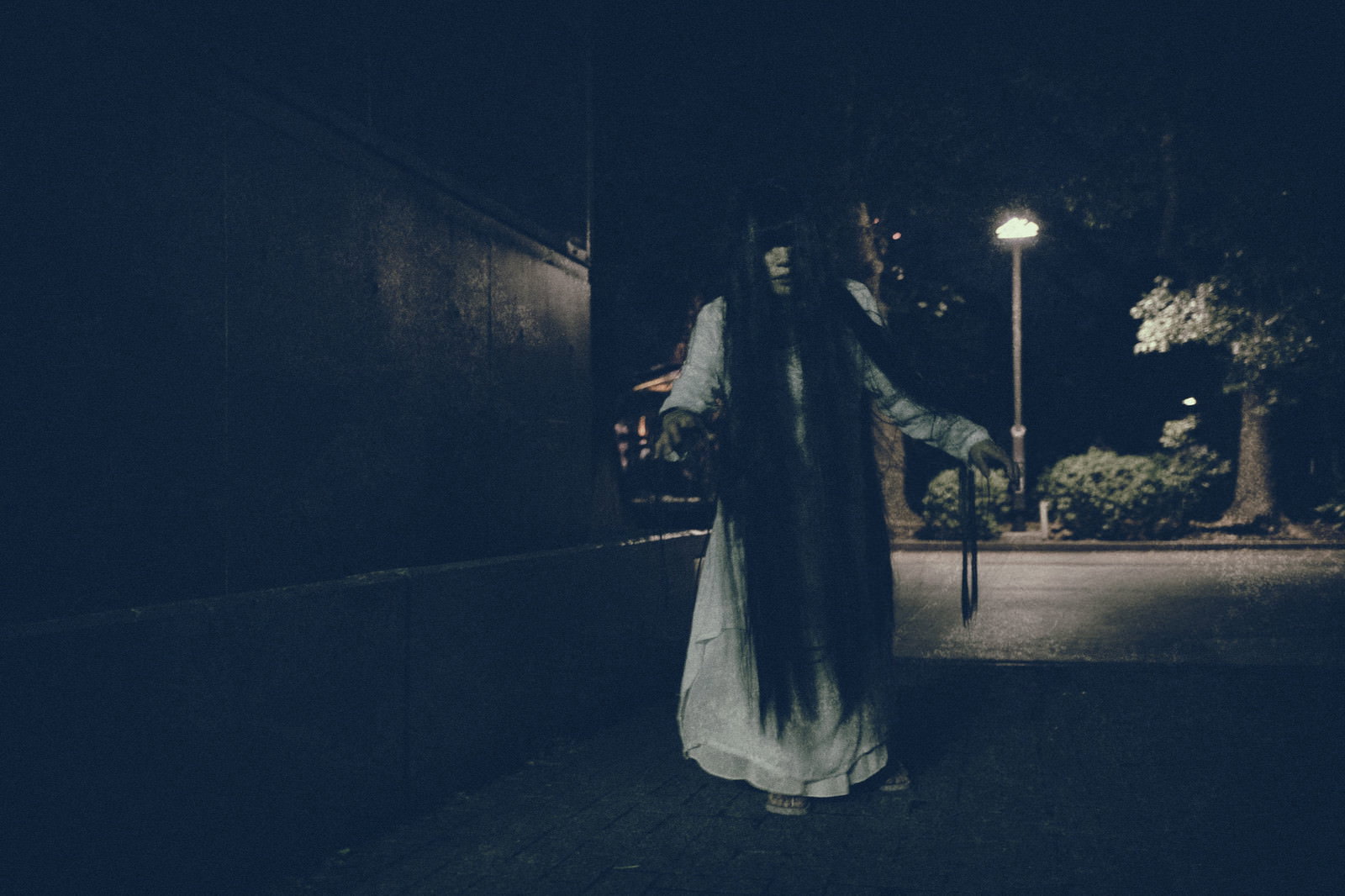 夜の公園で街灯の光を背に白い衣装で佇む女性［モデル：緋真煉］