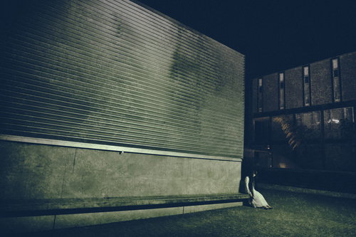 暗いコンクリート壁沿いに座る女性のシルエット