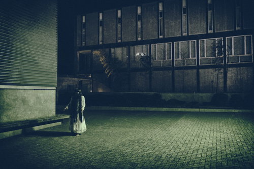 夜の石畳に立つ髪の長い不気味な女性のシルエット