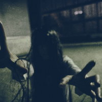 薄暗い空間で何者かにハグされる女性・怨念ハグの写真