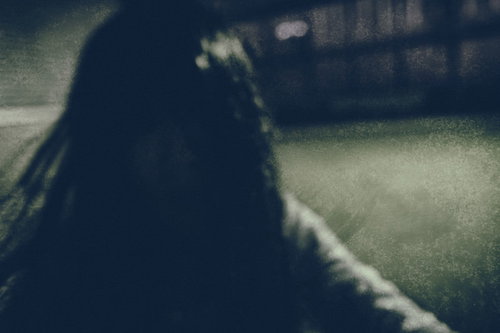 暗がりの中で髪を振り乱す女性