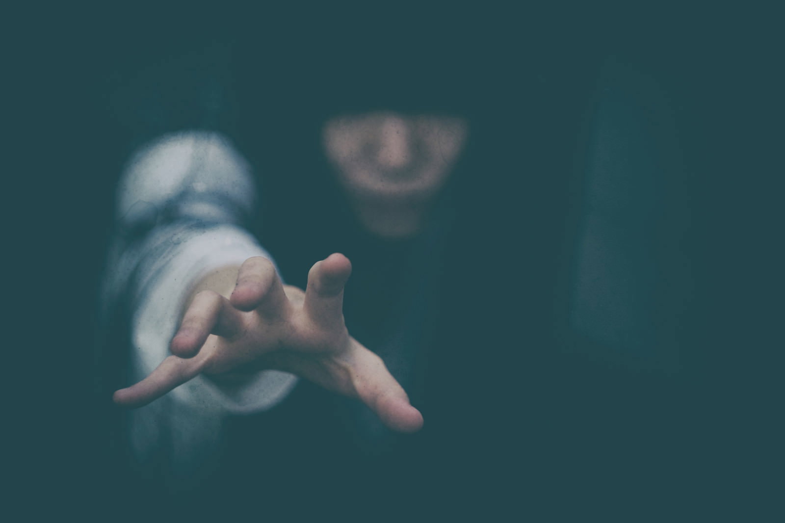 暗闇の中で前方に向かって手を伸ばす女性のホラーな雰囲気の写真［モデル：緋真煉］