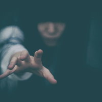 暗闇に追い詰められ手を伸ばす女性の恐怖表現の写真