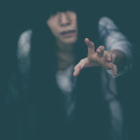 暗闇から手を伸ばして助けを求める女性の恐怖シーンの写真
