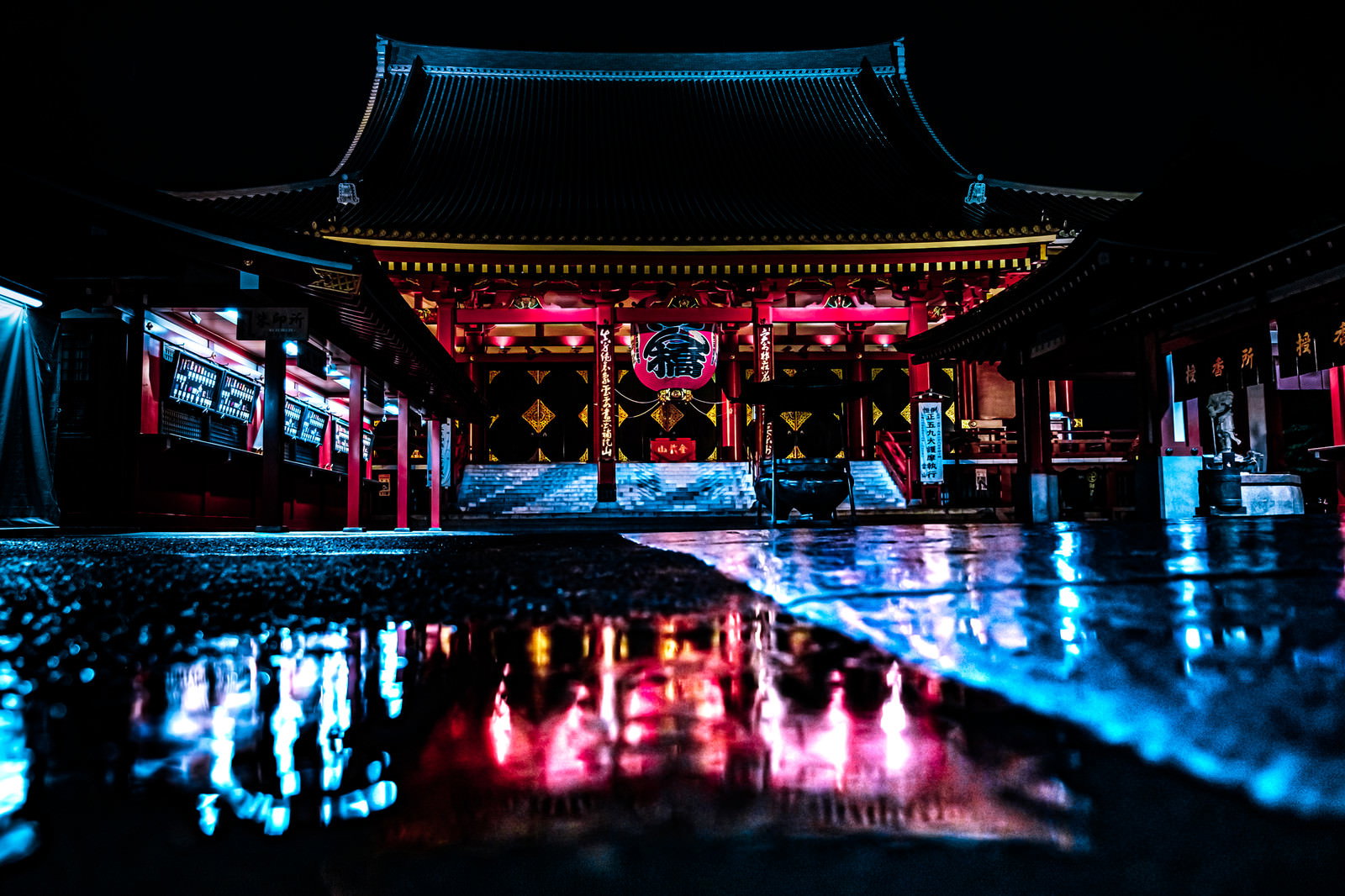 夜の浅草寺本堂と境内の水たまりに映る光の反射