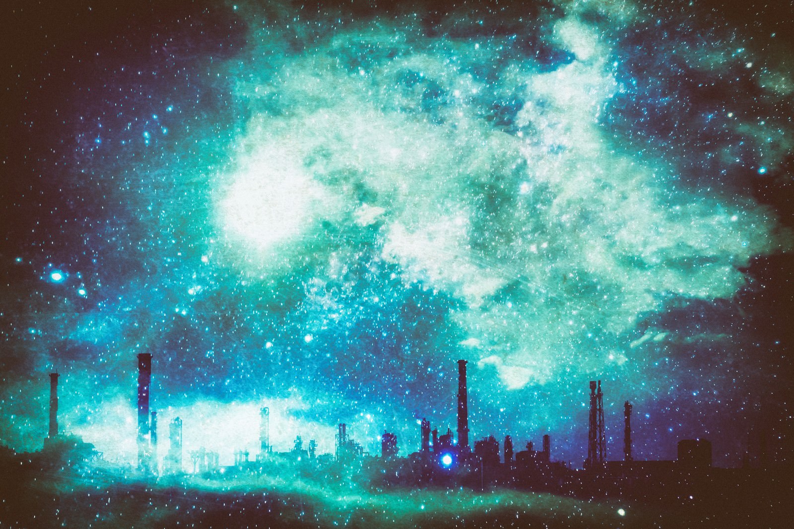 青緑色の星雲が広がる夜空の下に工場のシルエットが見える幻想的な夜景