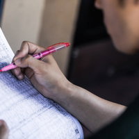 競馬新聞で予想を書き込む手元とピンク色のペンの写真