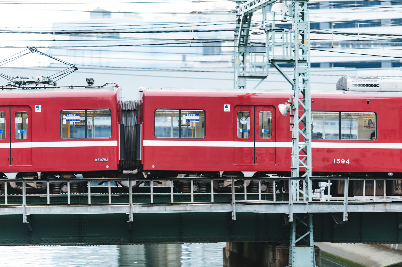 赤い車体の電車が陸橋を走行する京急逗子線の側面写真