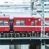陸橋を走り抜ける赤い電車の側面（京急逗子線）の写真