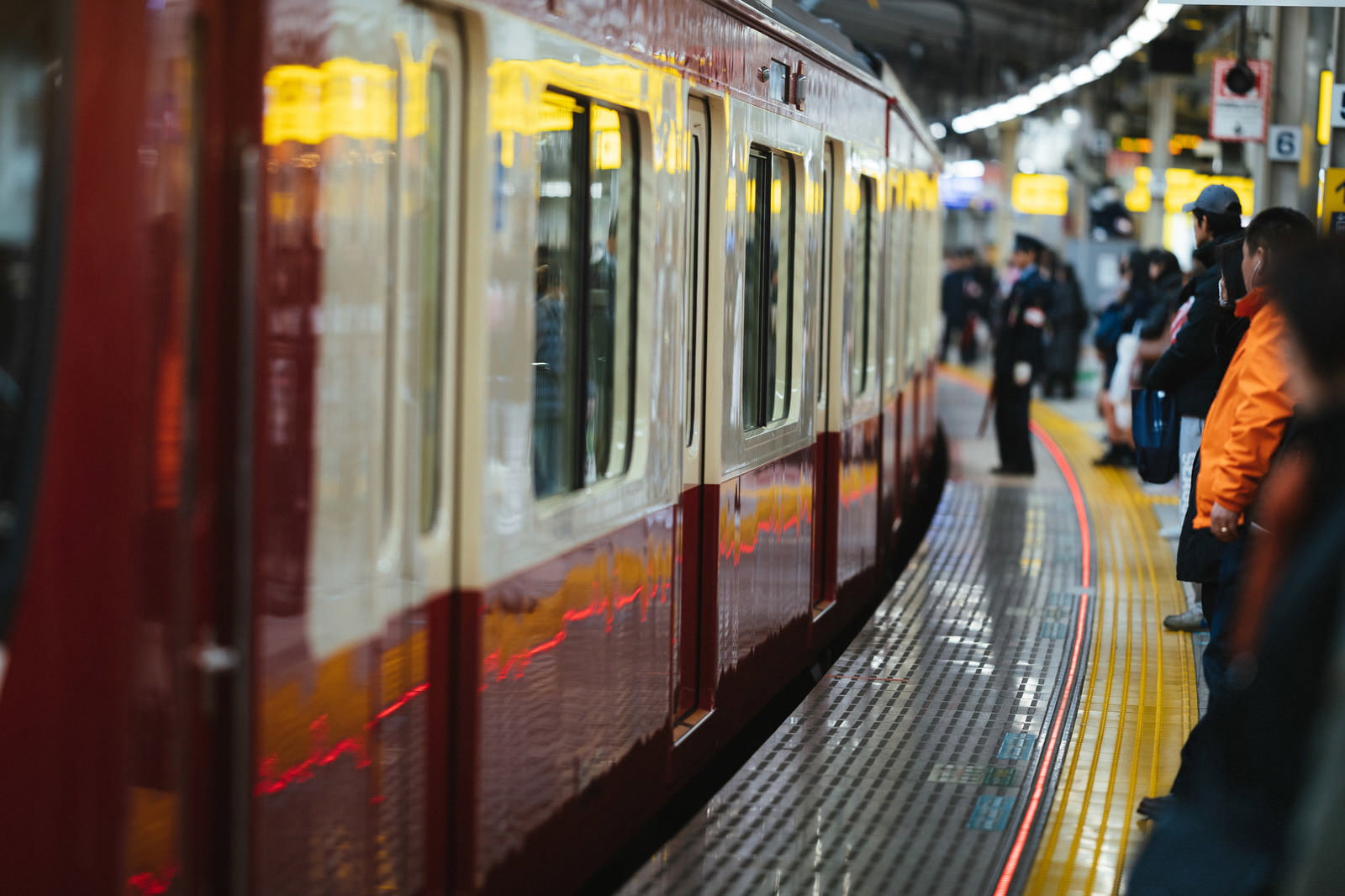 ホームで電車を待つ通勤客たちと停車中の車両