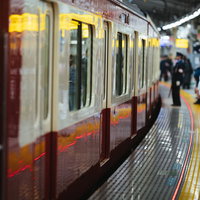 京急逗子線のホームで車両の停車を待つ通勤利用者達の写真