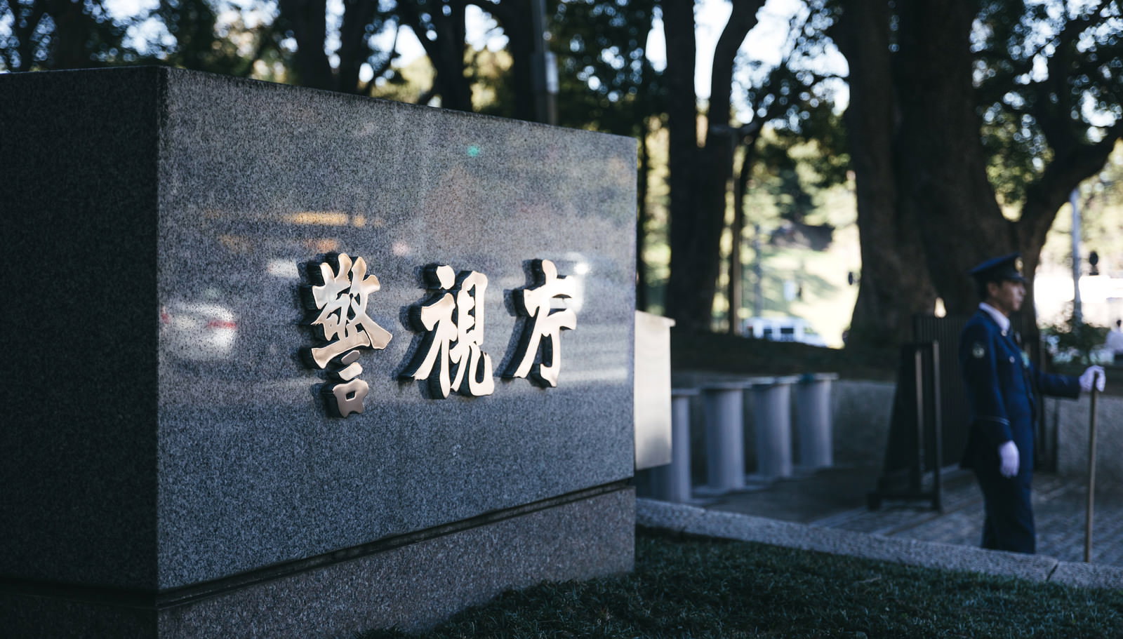 警視庁の看板前に立つ制服姿の警察官