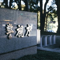 警視庁の看板前に立つ紺色制服姿の警察官の写真