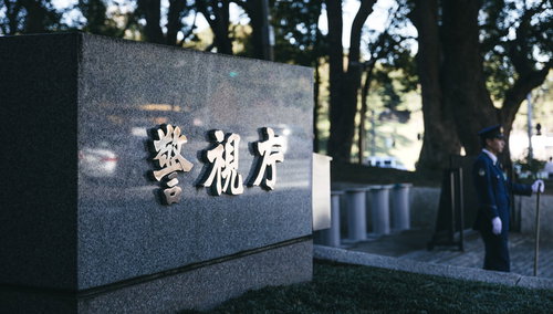 警視庁の看板前に立つ紺色制服姿の警察官