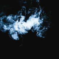黒背景にもくもくと広がる白い煙のアップの写真