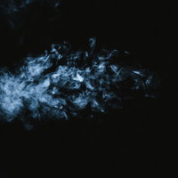 暗闇に浮かぶ消えそうな青白い煙の背景の写真