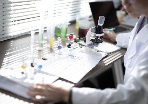 論文を書く研究者のデスク、分子構造模型と試験管で実験の様子を展開