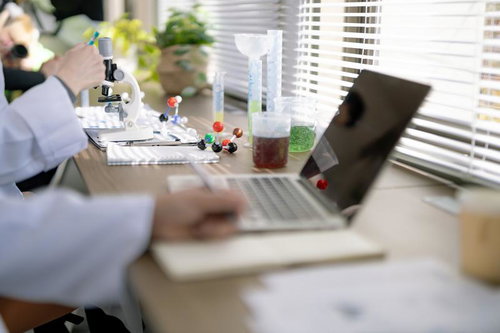 試行錯誤しながら論文を書く研究員と実験用機材