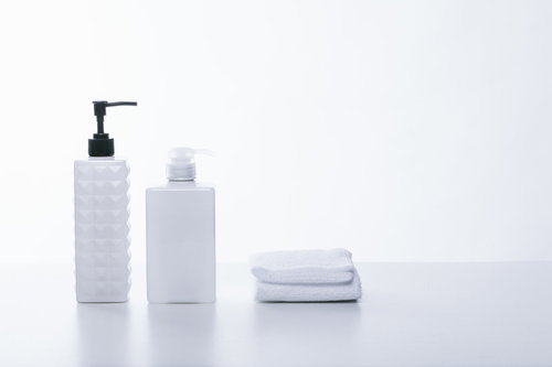 スキンケア用のボトル容器とタオルの白背景スタイリング