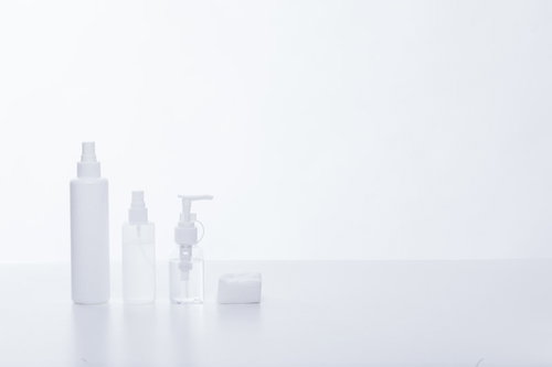 白い背景に並ぶスキンケアボトルとコットン