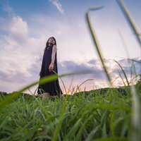 公園の草むらを彷徨く黒いワンピースの女性の写真