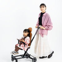 ピンクシャツの母親とB型ベビーカーに座る花柄ワンピースの女の子の写真