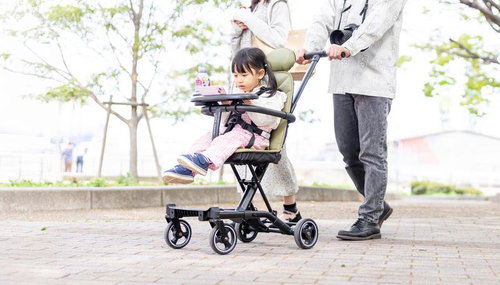 公園でベビーカーに座りスマホを見る女の子と母親