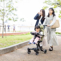 新緑の公園でベビーカーに乗る女の子と楽しく会話するママ友二人の写真