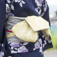 浴衣姿で帯結びを見せる女性の後ろ姿、帯締めの結び方の写真