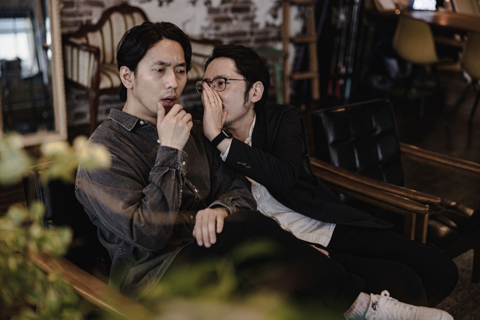 スーツを着た二人の男性が耳打ちで内緒話をしている写真［モデル：大川竜弥 ゆうせい］