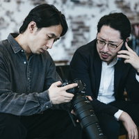 証拠の写真データを確認しながら依頼者に電話で報告する探偵ふたりの写真