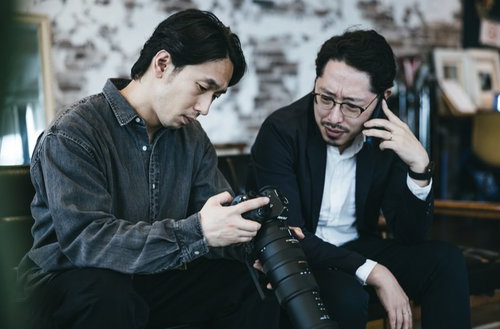 証拠の写真データを確認しながら依頼者に電話で報告する探偵ふたり